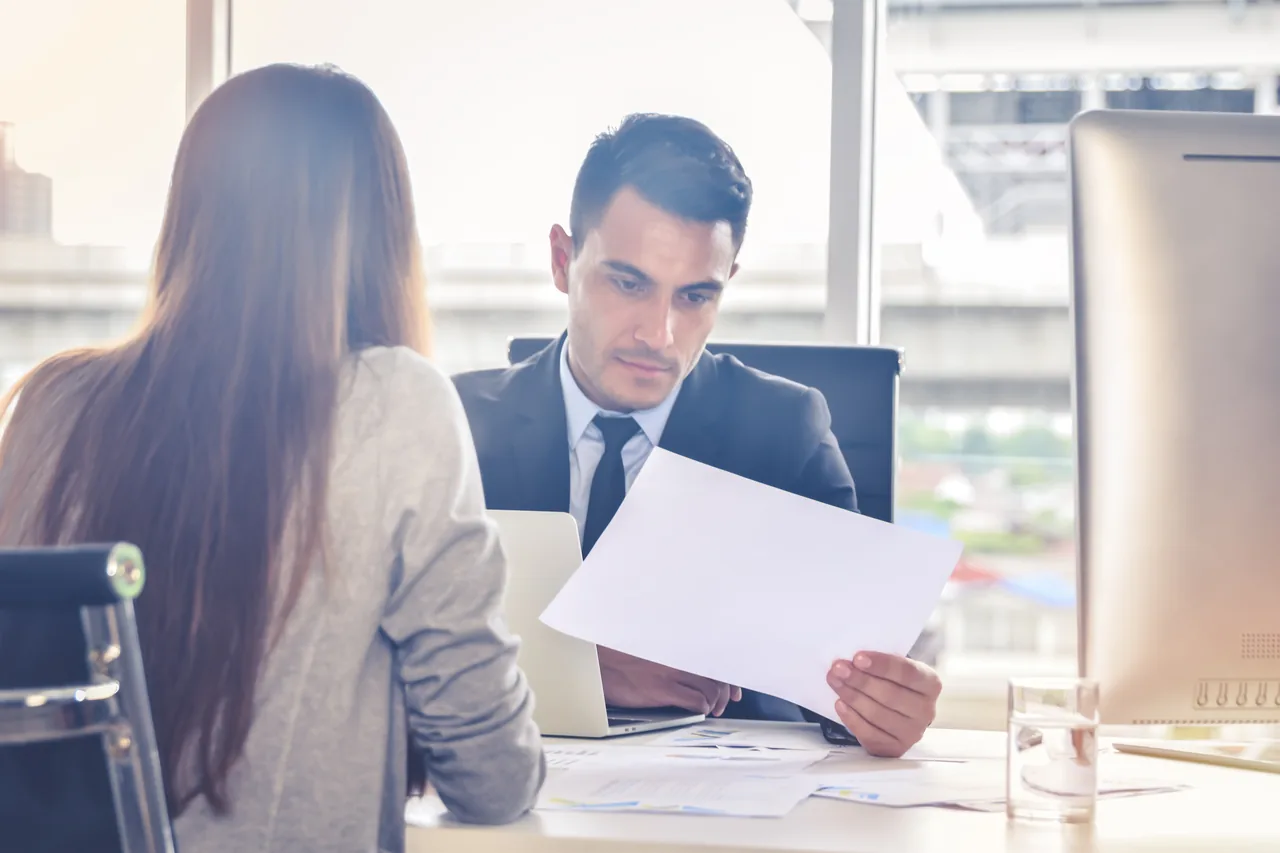 Two professionals reviewing documents together at an office desk