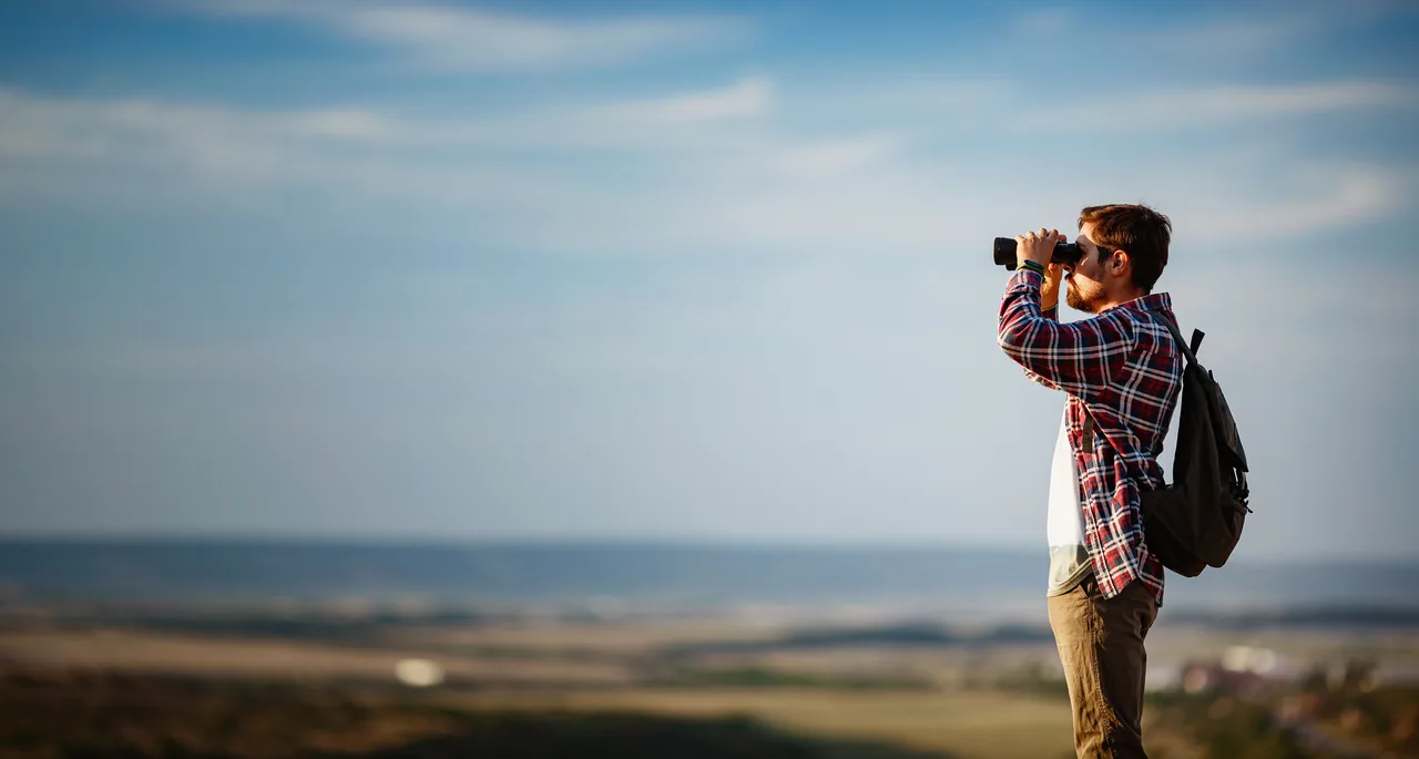 A hiker surveying the landscape through binoculars